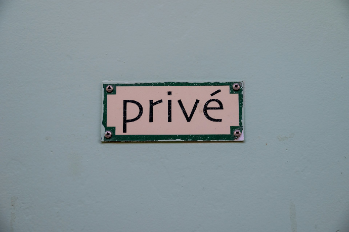 A rectangular sign reading "privé" mounted on a pale blue wall